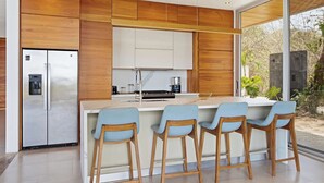 Uma cozinha moderna com armários de madeira, geladeira de aço inoxidável e um espaço bar com banquetas.