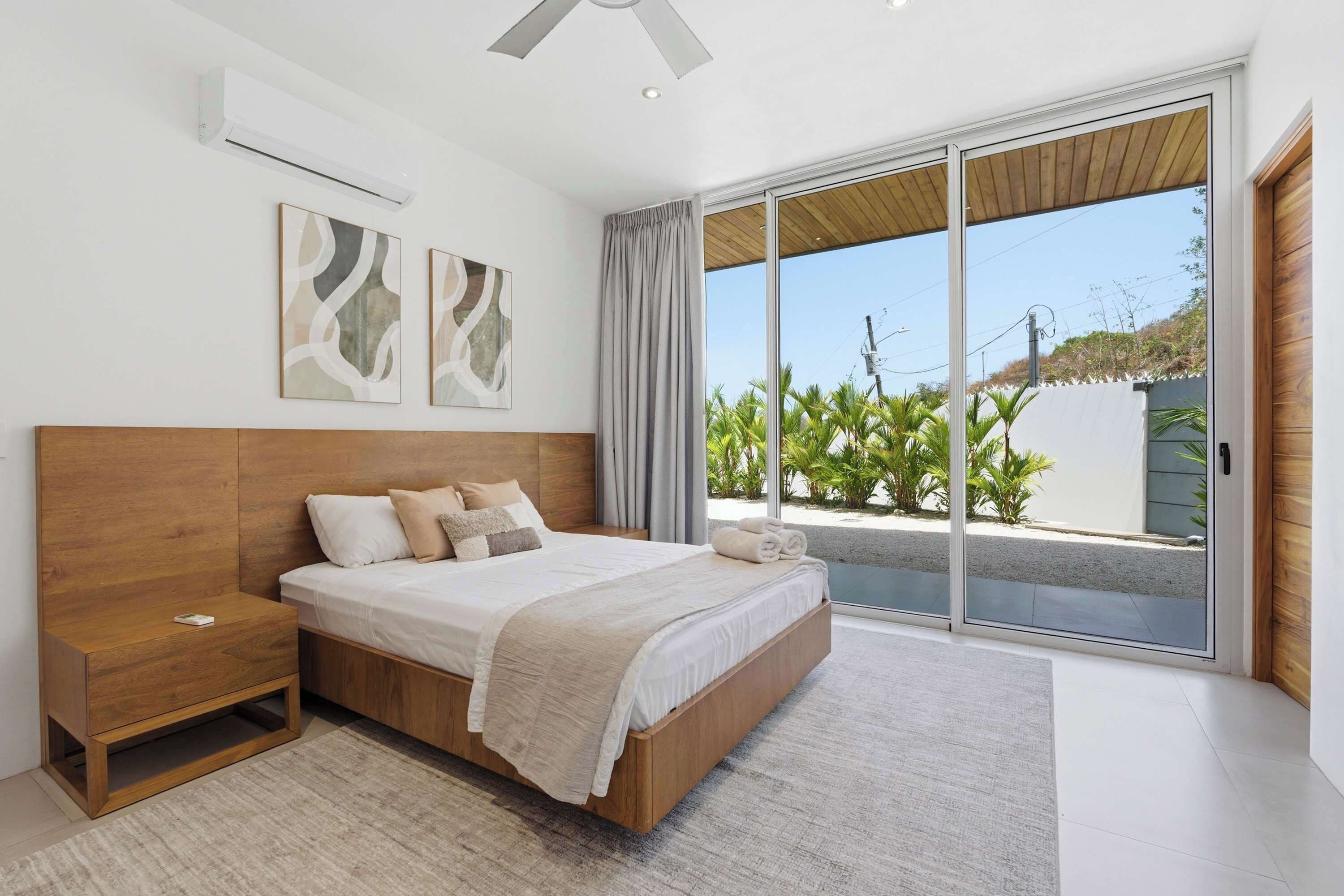 A bedroom with a bed, nightstand, and large sliding glass door to a balcony.