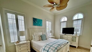 Una camera da letto con un letto, due comodini, una televisione e una ventola a soffitto.
