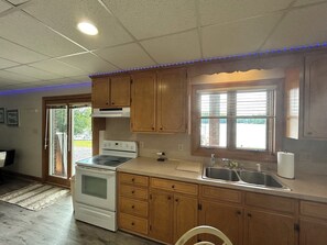 A kitchen with wooden cabinets, a stove, a sink, and a window with blinds. - Lakefront Paradise on Lake Hickory’s Main Channel – Handicap Accessible (Taylorsville)