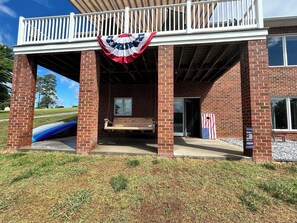A building with a covered porch, a bench, and a flag. - Lakefront Paradise on Lake Hickory’s Main Channel – Handicap Accessible (Taylorsville)