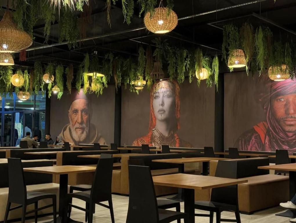 A restaurant with wooden tables and black chairs, hanging plants, and wall art.