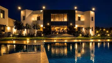 Un hotel moderno con piscina, un área exterior cubierta e ingreso bien iluminado.