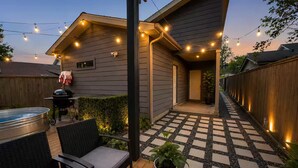 Ein Garten mit Terrasse, Gartenmöbeln, Grill und Lichterkette.