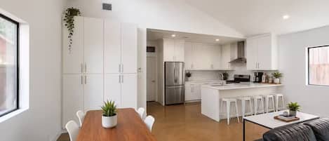 A modern kitchen with white cabinets, stainless steel appliances, and a central island with bar stools.