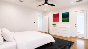 Ein Schlafzimmer mit Bett, Kommode, Deckenventilator und zwei Türen.