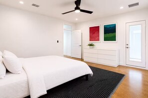 A bedroom with a bed, a dresser, a ceiling fan, and two doors. - Central Houston Bungalow Cowboy Pool & EV Charger (Houston)