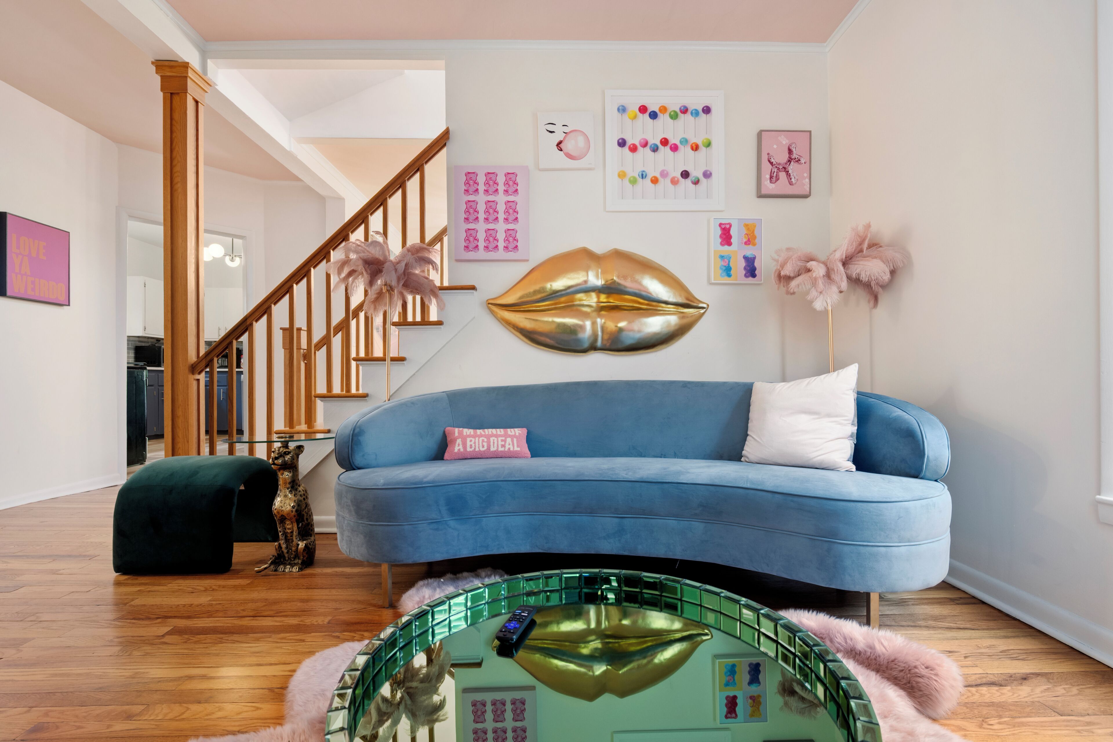 A modern living room with a blue sofa, a staircase, and a green coffee table.