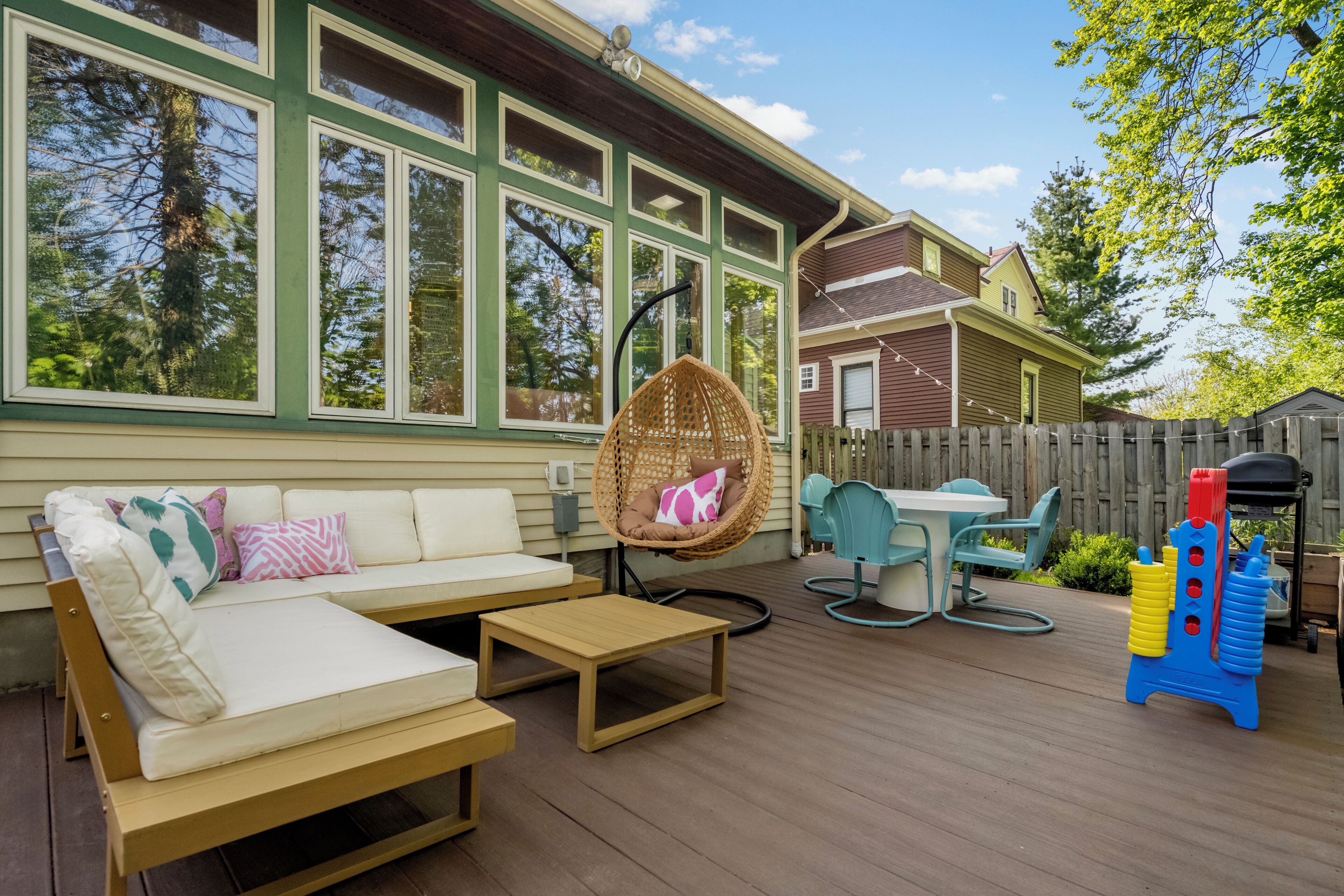 A deck with a sofa, chairs, a hanging chair, and a table.