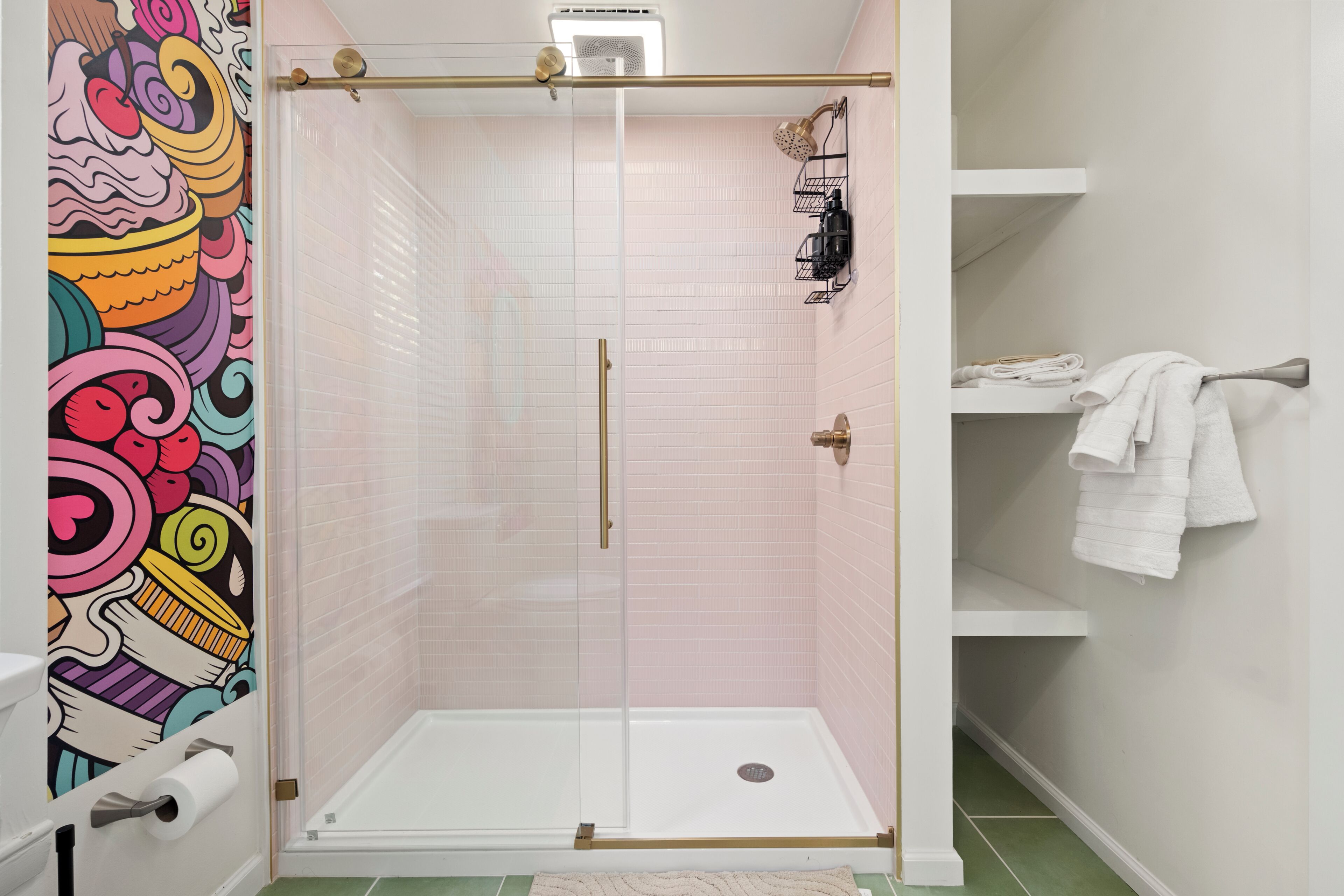 Eine Dusche mit Glastür, eine Toilette mit Toilettenpapierrolle und ein Handtuchhalter mit gefalteten Handtüchern.