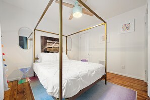 Un dormitorio con cama con dosel, ventilador de techo y ventana con vistas.