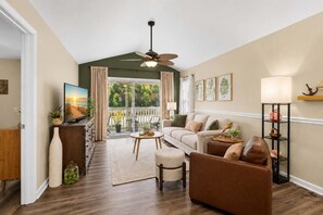 A living room with a sofa, armchair, coffee table, and a television on a stand. - Coastal Chic Golf Retreat Fairways 18F (Myrtle Beach)