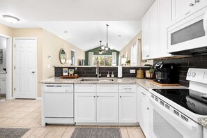 A modern kitchen with white cabinetry, a built-in oven, and a microwave. - Coastal Chic Golf Retreat Fairways 18F (Myrtle Beach)