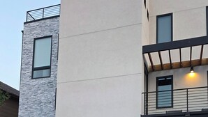 A modern two-story house with a garage, a wooden porch, and a stone facade.