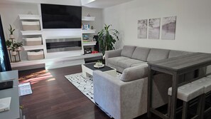 A modern living room with a grey sofa, a flat-screen TV, and a coffee table.
