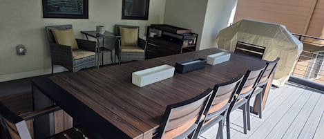 Un espace extérieur aménagé pour les repas, avec une table en bois, des chaises et un barbecue.