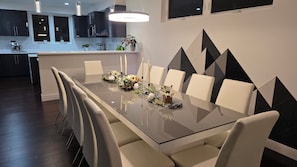 Un comedor moderno con una mesa de vidrio, sillas blancas y un diseño geométrico en la pared.