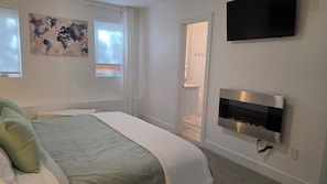 Un dormitorio con cama, televisor, chimenea y un mapa mundial en la pared.