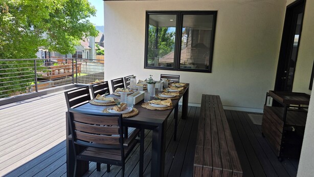 An outdoor dining area with a long table set for a meal, surrounded by chairs and benches.