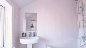 Un baño con un lavamanos blanco, un espejo y una ducha.