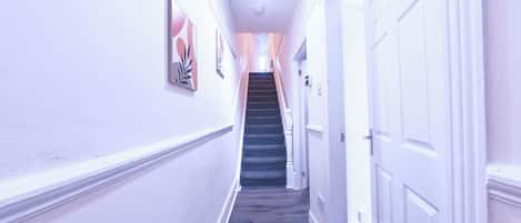 Un pasillo con una escalera que lleva a una puerta.