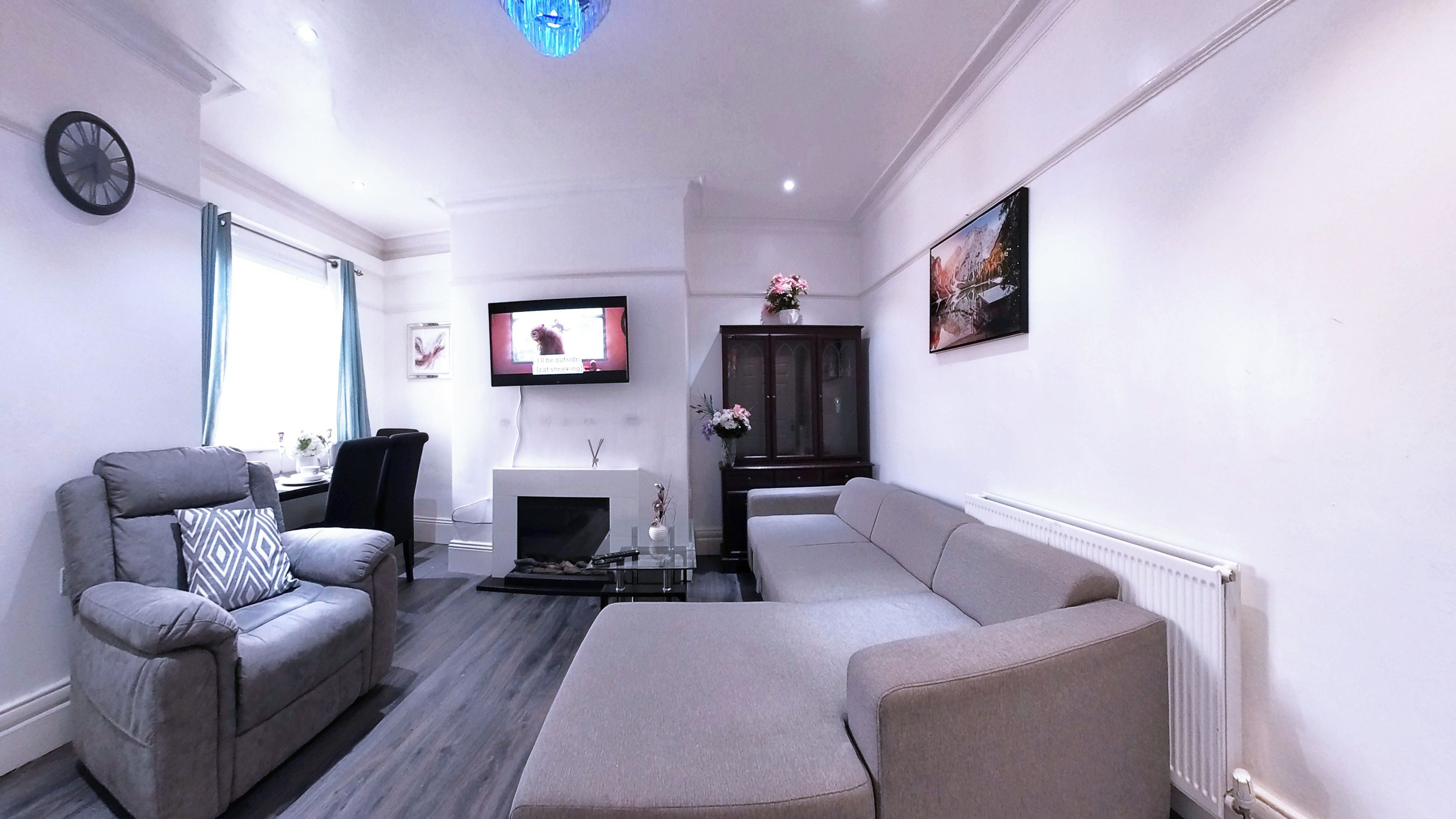 Una sala de estar con un sofá, un sillón, chimenea, televisor y un cuadro en la pared.