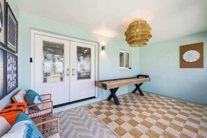 Ein Zimmer mit einem Tischtennisplatten, einer Couch mit Kissen, einer Wanduhr und einer dekorativen Leuchte.