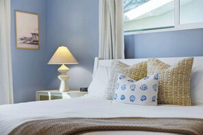 A neatly made bed with white bedding, a lamp on a bedside table, and a framed picture on the wall. - Private Dock • Pool • Hot Tub • Puttputt • Games (St. Petersburg)