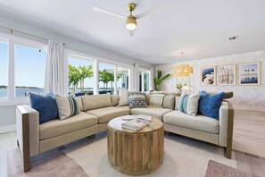 A modern living room with a sectional sofa, a round coffee table, and a ceiling fan. - Private Dock • Pool • Hot Tub • Puttputt • Games (St. Petersburg)