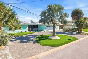 A residential property with a paved driveway, a well-maintained lawn, and a house with a light blue exterior. - Private Dock • Pool • Hot Tub • Puttputt • Games (St. Petersburg)