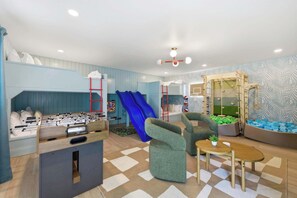Ein Kinderspielbereich mit Kicker, Rutschen und Klettergerüsten.