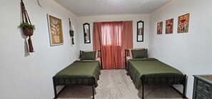 A bedroom with two single beds, a mirror, a plant, and artwork on the walls. - Amazing view! Charming 3-bedroom house in welcoming Anchorage neighborhood (Anchorage)