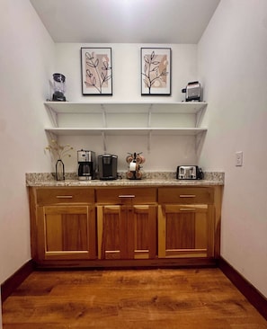 A kitchen with wooden cabinets, a countertop, a coffee maker, a toaster, and two framed wall art pieces. - Sugar Sand Sunset | Beachfront | Sleeps 20 (New Lisbon)