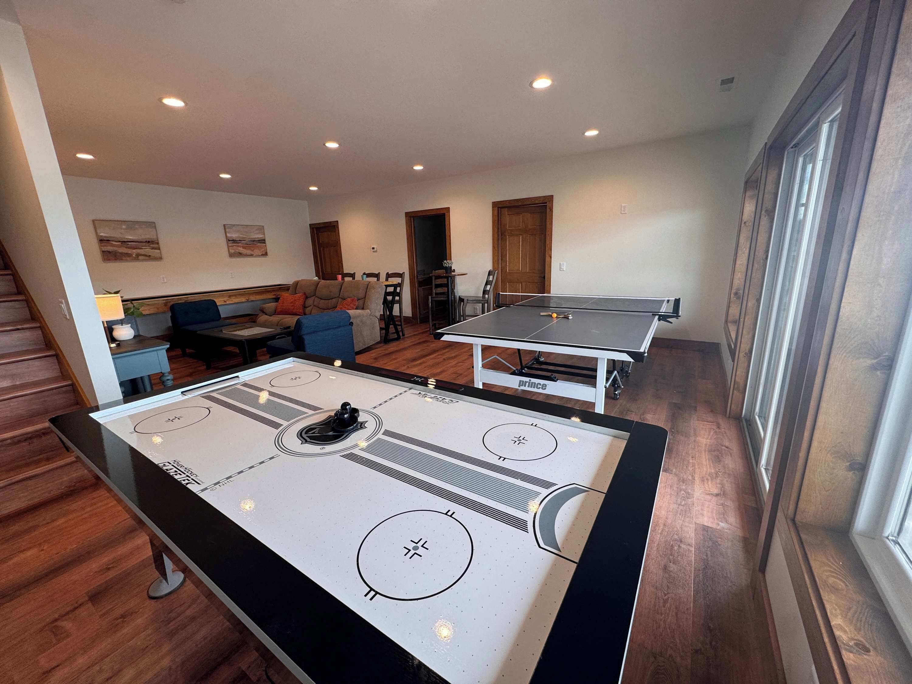 Una habitación con mesa de ping pong, mesa de fútbol y un sofá al fondo.