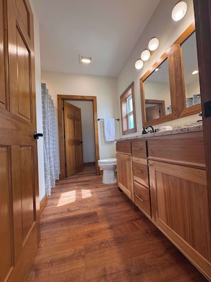 Un bagno con mobili in legno, un water bianco, uno specchio e una zona doccia.
