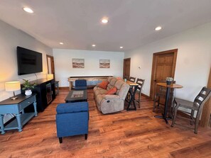 A living room with a sofa, coffee table, TV, and dining area with chairs and a table.