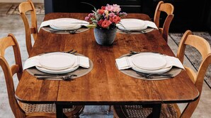 Una mesa de madera para comer con seis sillas, un florero con flores y una cocina moderna al fondo.