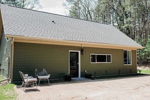 A single-story house with a sloped roof, a front door, and two windows. - Hidden Lake Escape | Hot Tub | Near Dells (Wisconsin Dells)