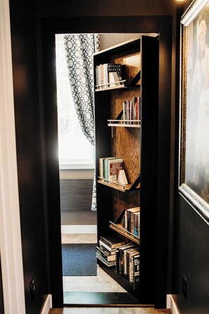 A hallway leading to a room with a large bookshelf filled with books. - Hidden Lake Escape | Hot Tub | Near Dells (Wisconsin Dells)