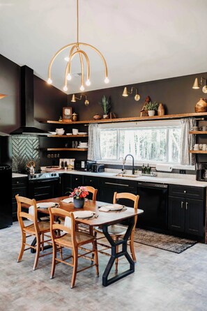 A modern kitchen with a central island, black cabinetry, and a hanging light fixture. - Hidden Lake Escape | Hot Tub | Near Dells (Wisconsin Dells)
