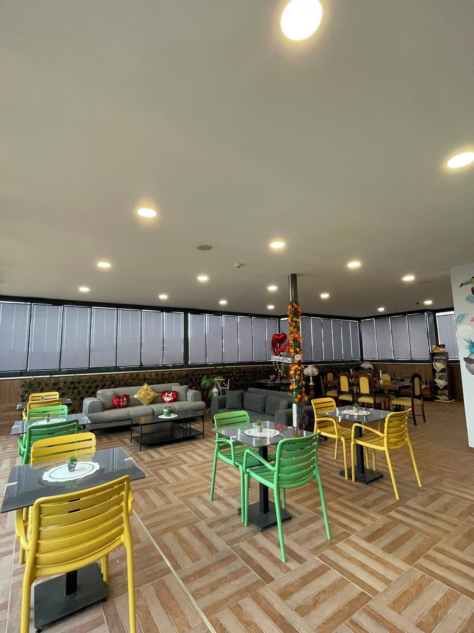 Un restaurante con varias mesas y sillas, un rincón con sofá y una columna decorativa.