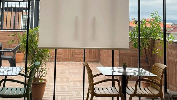 Een kamer met een groot raam, een wit scherm en een tafel met stoelen.