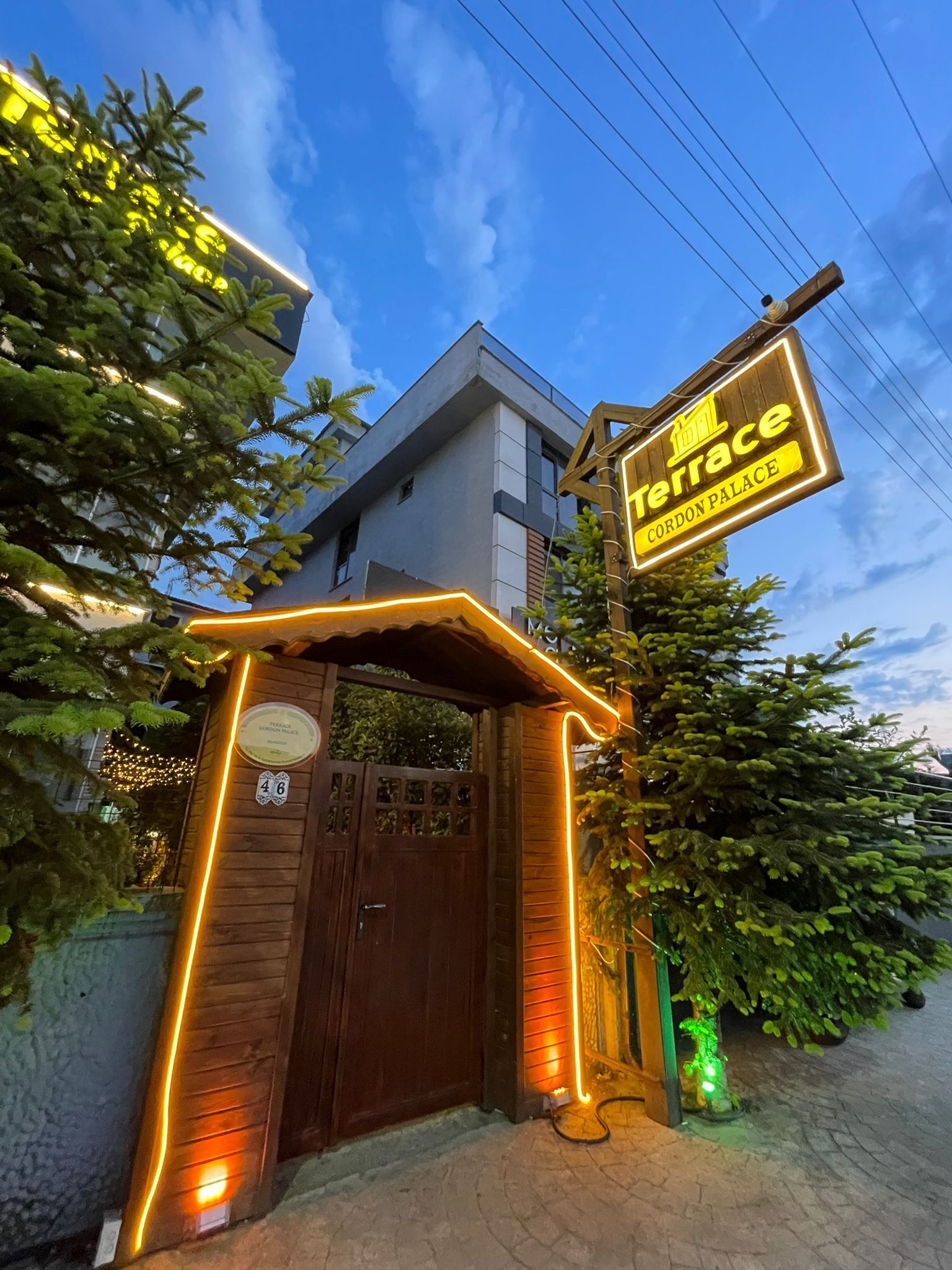 A building entrance with a sign for 'Terrace Cordon Palace' and a wooden gate.