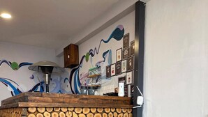 Een bar met houten toonbank, een stapelhout, een turquoise schommelstoel en een muur versierd met afbeeldingen van koffie.