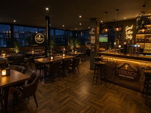 Zona de bar con mostrador de madera, varios taburetes y un letrero de neón que dice 'Good Vibes Only'.