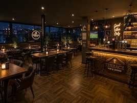 Zona de bar con mostrador de madera, varios taburetes y un letrero de neón que dice 'Good Vibes Only'.