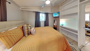 A bedroom with a bed, a television, a ceiling fan, and a window with curtains. - Al & Sherry's Oasis (Rockport)