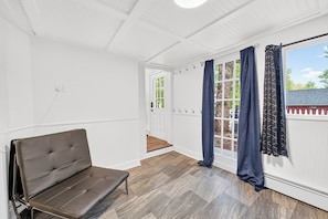 Une pièce avec un banc, une porte donnant sur l’extérieur et une fenêtre avec des rideaux.