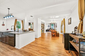 A spacious kitchen with a central island, wooden flooring, and modern lighting fixtures.