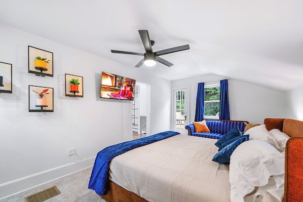 Une chambre à coucher avec un lit, un canapé, un ventilateur de plafond et un téléviseur.